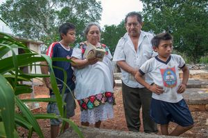 Doña Celestina Pat, Don Antonio Moo Argona and two of their grandchildren visit the grave of Antonio's mother.
