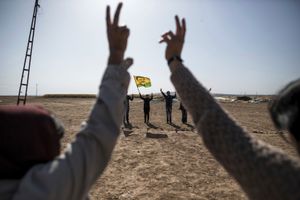 A woman holds a flag with a portrait of the detained Kurdistan Workers Party (PKK) rebel leader Abdullah Ocalan, during a Kurdish people demonstration, in the southeastern border village of Mursitpinar, Sanliurfa province, Turkey on November 10, 2014, near the Syrian town of Kobane, also known as Ain al-Arab.