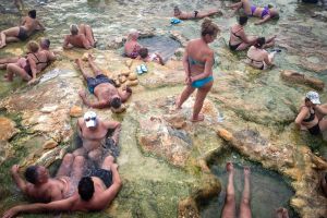 Tourists getting cosy in the thermal waters on the shores of the Aegean Sea, Greece Avgust 2017
