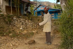 Haiti woman sweeping outdoors