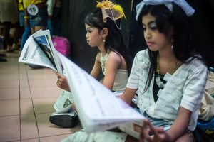 Two contestants read the newspaper while on a break during a beauty pageant, Yogiakarta