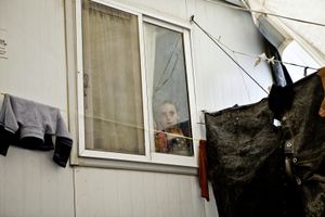 A young child looks outside from his family's container home. © Tom Verbruggen