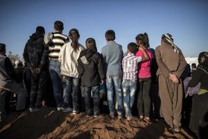 Kurdish people watch the funeral of  a Kurdish Protection Unit (YPG) and Women's Protesction Unit (YPJ) fighters in Suruc, Turkey on November 7, 2014.