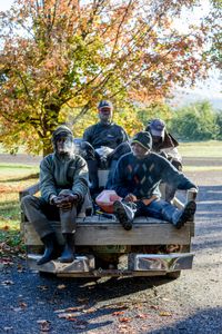 Baltimore, Kenroy, Hernal, and Rodger ride in the back of a pickup truck to the orchard fields