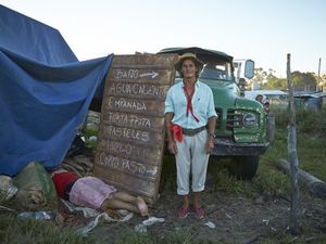 Gauchito Gil devotee posing for the portrait while his partner is asleep after the long day of celebrations  of January 8, date of the murder of the popular saint