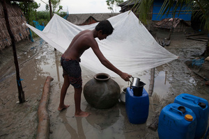 A boy collects rainwater by using a plastic sheet, as they have no tin roof. Rainwater is the main source of drinking water of the Shyamnagar villagers. Satkhira, Bangladesh