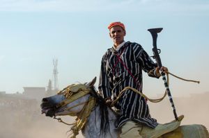 A rider stand on his mount amidst the dust and gunpowder smoke after a successful charge. Seffrou, Morocco