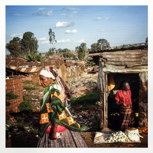 An elderly woman passes the main valley of Kibera which is filled with shacks covered with corrugated iron. The Kibera slum is the largest slum in Nairobi with around half a million inhabitants.
