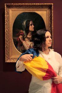 Poet Magda Cârneci in fron of the painting of Constantin Daniel Rosenthal representing Revolutionary Romania, © National Museum of Art, Bucharest