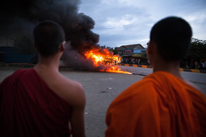 Monks watch burning police cars after mobs attacked them at Stung Meanchey District in Phnom Penh.