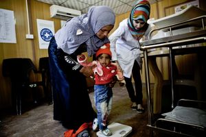 A nurse for Médecins du Monde helps a mother weigh her child. © Tom Verbruggen