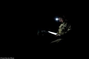 Soldier Reads Bible in Dark Dugout