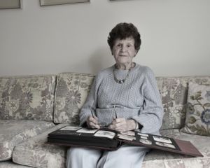Nanny on the living room couch, looking through an early album from the 1940s.