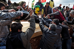 At a cemetery in Kobane, Syria, on 2 April, 2015, Kurdish men take out a corpse of a fighter from a coffin before lowering it into the ground, as people attend the funeral of a Kurdish People's Protection Unit (YPG) who was killed during clashes with the Islamic State in one of the frontlines of Kobane, Syria.