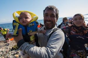 A refugee from Syria holds a baby just after reaching the shore at Lesvos island. More than 30,000 refugees had reached the Greek island of Lesvos during August 2015, according to Amnesty International.  August 22, 2015, Lesvos, Greece