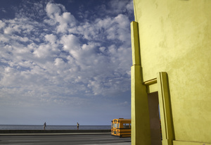 Late afternoon sky, Yellow building and school bus on the Malecón in Havana.