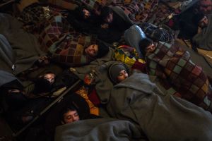 Early morning in the warehouse, refugees are sleeping with each other to keep them warm.