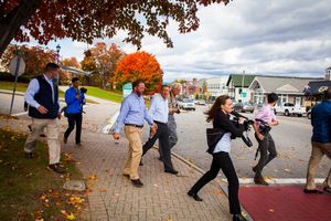 Surrounded by staff and members of the media, Republican presidential candidate Gov. John Kasich (fourth from left) of Ohio walks to Biederman's Deli in Plymouth during a campaign bus tour through New Hampshire on Wednesday, Oct. 14, 2015.