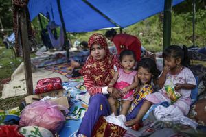 A mother with her daughters take rest in a makeshift tent following the earthquake in Pidie Jaya, Aceh province, on December 10, 2016.