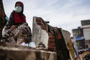 A woman sat on the rubble of her shop during search and rescue operation at the collapsed building in Pidie Jaya, Aceh province, on December 10, 2016.