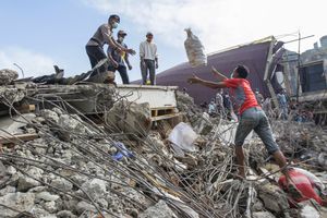 Volunteer throw an items that survived to Indonesian policeman during search and rescue operation at the collapsed building in Pidie Jaya, Aceh province, on December 10, 2016.