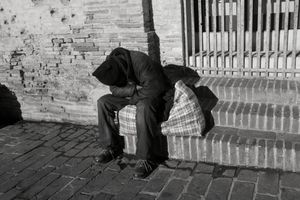 Homeless man sleeping on a bag containing his few belongings