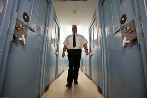 A male prison officer walks down the corridor of one of the residential wings. HMP Send, closed female prison. Ripley, Surrey.