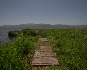 There is a path through the fields, a lake in between and in further, a mountain