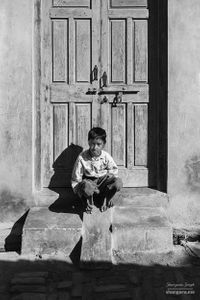 Boy sitting on front doorstep  | Dhesian Sang, Punjab.