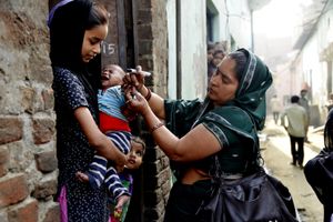 A vaccinator vaccinates a child on the house to house vaccination day in Bhujpura, Aligarh, Uttar Pradesh