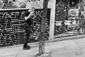 Man pausing to read messages in Soho