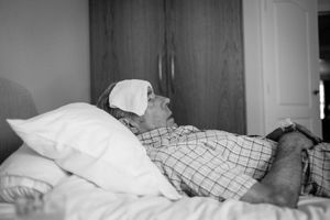 Resting with a cold flannel on his forehead to try and reduce a temperature.