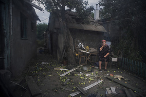 A Luhansk citizen sits outside her destroyed house