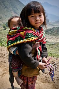 Young H'mong girl with a baby in the rice terraces near Ta'van village selling bracelets to tourists trekking in the region.