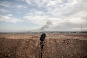 A microphone stands on the media hill in Mursitpinar on the outskirts of Suruc, as smoke rises from an Islamic State position in the town of Kobane after an airstrike led by the US coalition, near the Turkey-Syria border on November 6, 2014.