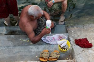 Old man is washing his clothes beside the pool