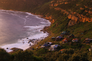 Smitswinkel Bay, the village at sunrise / Smitswinkel Bay (the Blacksmith's Shop Bay) at 5:00am on a cold and windy early summer morning. This village can only be reached by a footpath and occasionally some Southern Right Whales can be seen in the bay close to shore.Strong wind as usual, as can be seen from the bush in the foreground.