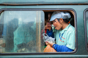 A woman eats while she waits for her minivan to take her home after her shift at a garment factory in Kampong Speu province, Cambodia.