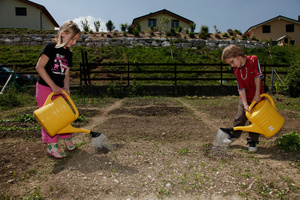 Enfants dans le jardin scolaire dans un nouveau quartier de villas. Kids gardening in a new neighborhood