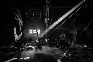 Refugees sweeping floor inside a temporary shelter, despite the conditions in which they are, they try to keep the place in good condition.  Belgrade, Serbia.