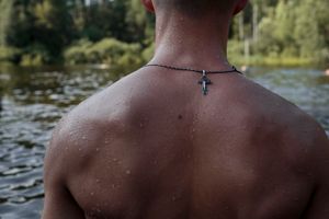 Dmitri (Dima) Antonets (17) escapes the heat during an afternoon off at the lake. 31 July 2016, Diveevo, Russia. He wears a Russian Orthodox cross for safety during his travels from Stavropol to Diveevo. "Orthodox Warrior" camp takes place in Diveevo, the center of pilgrimage for Orthodox Christians in Russia.