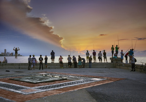 People stand on the Malecón along Havana's seafront at sunset.