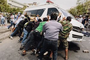 Anti-government protesters overturn an ambulance following clashes between demonstrators and police.