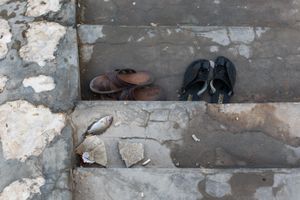 Sandals and a dead fish on the stairs of the pool