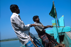Men wearing lungis hoisting anchor near Teknaf, Bangladesh