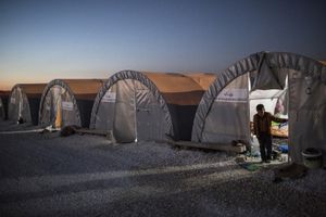 A Syrian Kurdish boy stands at the entrance of his family tent during evening time in 'Arin Mirhan' refugee camp in the border town of Suruc, Turkey on November 7, 2014.