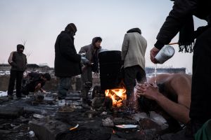 Showering at very low temperatures and in very bad conditions, migrants showering every day in this place so that heat water in a barrel.