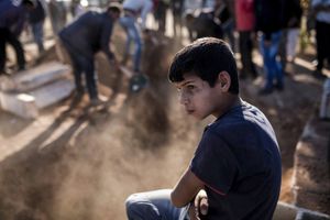 A young boy looks on as mourners cover with soil the grave of a Kurdish Protection Unit (YPG) fighter who died during fighting in the besieged Syrian border town of Kobane, in the town of Suruc, Sanliurfa province, Turkey on November 6, 2014.