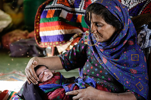 Chasing flies, A grandmother of the Jat tribe, caring for her grandson while his mother is working on the fields. - Gujarat - India
