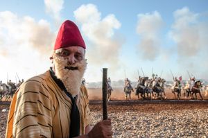A costumed, wandering actor entertains the fantasia crowd with traditional skits. Oulad Haddou , Bouskoura, Morocco